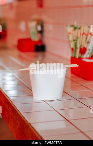 Contenitore da asporto cinese con bacchette sul tavolo al ristorante Foto Stock