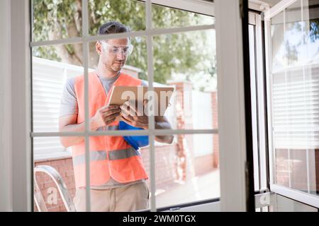 Il tecnico addetto alla manutenzione legge il documento sugli appunti vicino alla finestra Foto Stock