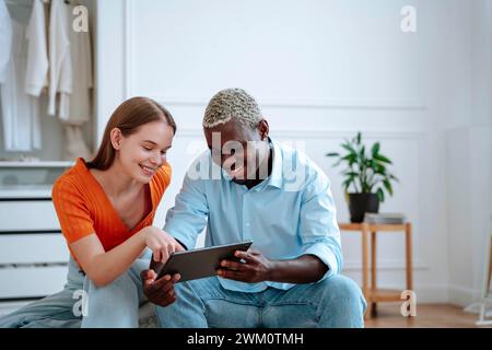 Giovane uomo e donna felici che usano un tablet PC a casa Foto Stock