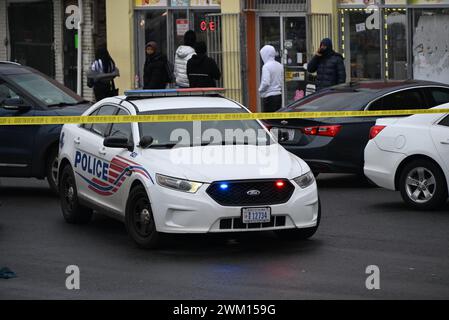 Washington, DC, USA. 23 febbraio 2024. (NUOVO) agenti di polizia sulla scena di una sparatoria al 300 Block of 63rd Street, ne, che ha lasciato una persona ferita e una persona morta a Washington, DC. 23 febbraio 2024, Washington, DC, USA: Diversi indicatori di prova hanno perlustrato l'area in cui si trovavano le casse di proiettili sulla scena del crimine e una tenda poteva anche essere vista sulla scena del crimine che copriva l'individuo dichiarato morto sulla scena. Un cartello "Welcome to Washington, DC" con i graffiti "F*** Biden" e' visto con la scena delle riprese in lontananza. La sparatoria ha avuto luogo intorno alle 5:30 DEL mattino, venerdì mattina Foto Stock