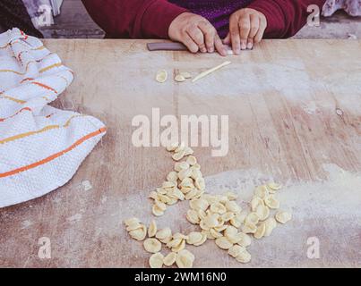 Primo piano sulle mani di una donna che prepara le orecchiette, la tipica pasta pugliese, per strada nel centro di Bari, regione Puglia, Italia meridionale, E. Foto Stock