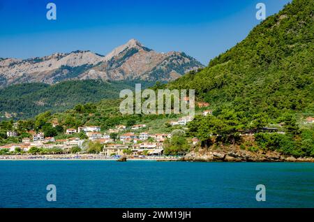 Un villaggio incastonato tra torreggianti montagne a Thassos, Grecia Foto Stock