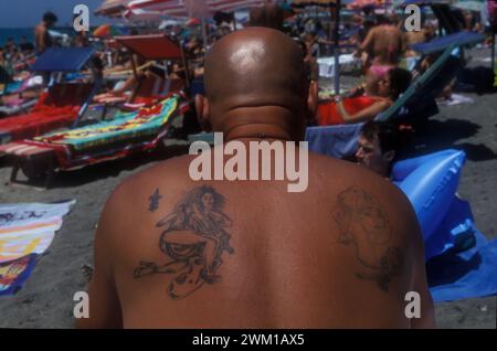 4066277 Lido di Ostia, Italia; (add.info.: Ostia Lido, 1999. Uomo tatuato. Ostia è una città balneare vicino a Roma. Nel periodo estivo molti abitanti di Roma si recano al mare, in particolare i giovani della periferia, hanno detto nello slang 'coatti' / Lido di Ostia, 1999. Uomo tatuato. Ostia è la spiaggia dei romani. D'estate è frequentata in particolare dai giovani che abitano le borgate della periferia, i cosiddetti "coatti"-); © Marcello Mencarini. Tutti i diritti riservati 2024. Foto Stock