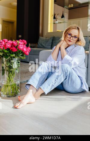 Corpo completo verticale di bella donna caucasica matura che indossa occhiali rilassanti a casa. Foto Stock