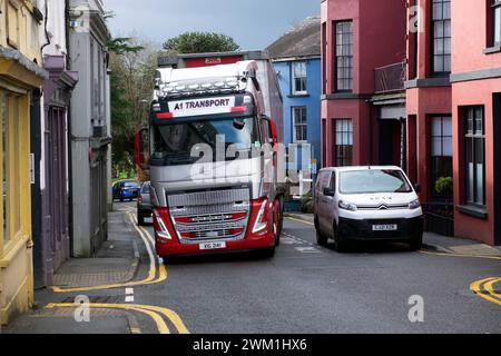 Autocarro HGV che guida su Rhosmaen Street, oltrepassa le auto parcheggiate all'esterno dei negozi, il percorso principale e stretto attraverso una piccola strada nella città di Llandeilo, Galles, Regno Unito 2024 Foto Stock