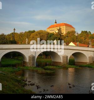 Bellissimo castello antico con un ponte sul fiume al tramonto. Vecchia architettura europea. Namest nad Oslavou - una città della Repubblica Ceca. Foto Stock