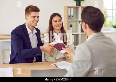 Felice giovane coppia in viaggio e incontro con il loro agente di viaggio o il gestore dei visti Foto Stock