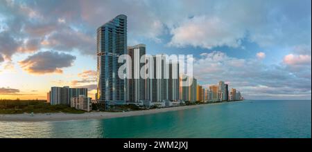 Alti hotel e condomini costosi sul fronte spiaggia sabbiosa sulla costa dell'oceano Atlantico nella città di Sunny Isles Beach al tramonto. Infrastrutture turistiche americane Foto Stock