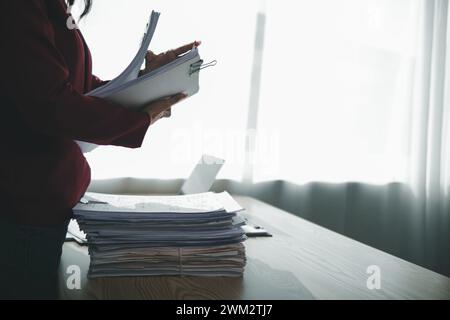 Un giovane segretario riceve una serie di documenti per trovare informazioni importanti che il manager dell'azienda può utilizzare in una riunione. Il concetto di trovare l'impor Foto Stock