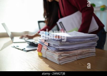 Un giovane segretario riceve una serie di documenti per trovare informazioni importanti che il manager dell'azienda può utilizzare in una riunione. Il concetto di trovare l'impor Foto Stock