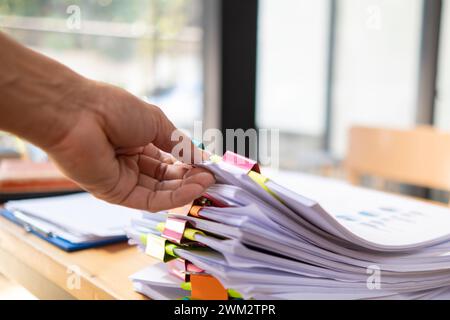 Un giovane segretario riceve una serie di documenti per trovare informazioni importanti che il manager dell'azienda può utilizzare in una riunione. Il concetto di trovare l'impor Foto Stock