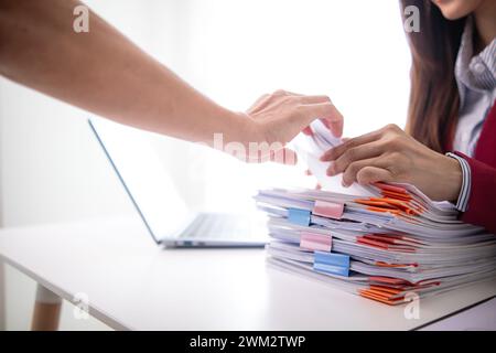 Un giovane segretario riceve una serie di documenti per trovare informazioni importanti che il manager dell'azienda può utilizzare in una riunione. Il concetto di trovare l'impor Foto Stock