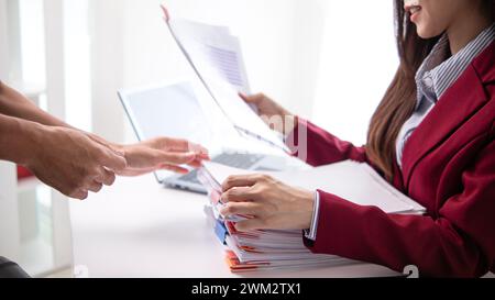 Un giovane segretario riceve una serie di documenti per trovare informazioni importanti che il manager dell'azienda può utilizzare in una riunione. Il concetto di trovare l'impor Foto Stock