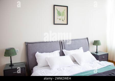 Letto disordinato con biancheria da letto grigia e bianca e cuscini Foto Stock
