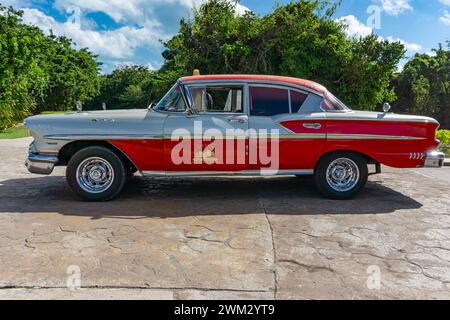 Cuba 14 febbraio 2016 - Un'auto d'epoca rossa e bianca in un parcheggio sotto un cielo blu a Cayo Santa Maria, Cuba. Foto Stock