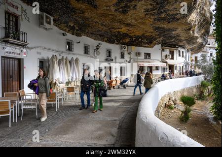 Tipiche grotte di strada del sole a Setenil con ristoranti e case all'interno delle rocce della montagna e turisti che camminano intorno a Cadice, Spagna. Foto Stock