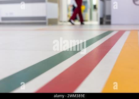 Linee guida colorate sul pavimento del corridoio dell'ospedale per la navigazione con sfondo dell'ospedale sfocato Foto Stock