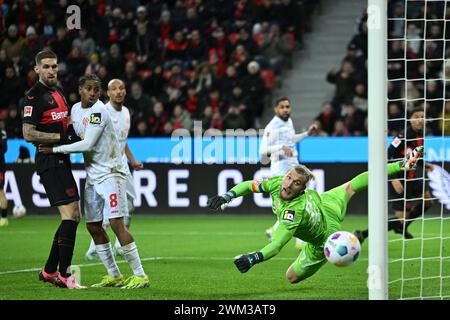 Leverkusen, Germania. 23 febbraio 2024. Calcio: Bundesliga, Bayer Leverkusen - FSV Mainz 05, giorno 23 presso la BayArena, Robert Andrich (l) del Leverkusen contro il portiere del Mainz Robin Zentner (r). NOTA IMPORTANTE: In conformità con le normative della DFL German Football League e della DFB German Football Association, è vietato utilizzare o far utilizzare fotografie scattate nello stadio e/o della partita sotto forma di immagini sequenziali e/o serie di foto video. Credito: Marius Becker/dpa/Alamy Live News Foto Stock