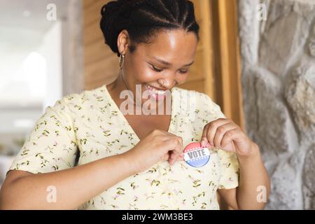 Una giovane donna birazziale le spilla un adesivo "Vote" sulla camicia Foto Stock