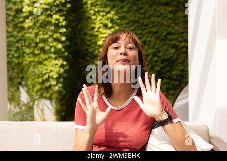 Una giovane donna birazziale ondeggia alla telecamera durante una videochiamata Foto Stock