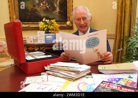 Re Carlo III legge carte e messaggi, inviati dai benestanti dopo la sua diagnosi di cancro, nella stanza del XVIII secolo della suite belga a Buckingham Palace, Londra. In seguito all'annuncio della diagnosi del cancro del re, il team di corrispondenza a Buckingham Palace ha ricevuto più di 7.000 lettere e schede in tutto il mondo. Al re è stata inviata una selezione nella sua scatola rossa quotidiana di documenti. Data foto: Mercoledì 21 febbraio 2024. Foto Stock