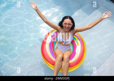 La giovane donna birazziale gode di una giornata di sole in piscina, con spazio per fotocopie Foto Stock