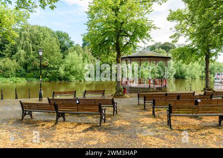 Bancarelle e panche boscose in un parco sulle rive di un fiume in una soleggiata giornata estiva Foto Stock