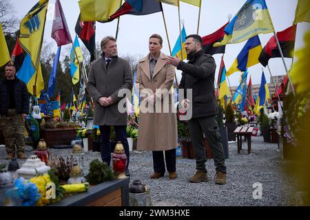 Leopoli, Ucraina. 23 febbraio 2024. Il primo ministro danese mette Frederiksen, centro, marito Bo Tengberg, sinistra, e il presidente ucraino Volodymyr Zelenskyy, destra, rendono omaggio al campo di Marte all'interno del cimitero di Lychakiv, 23 febbraio 2024 a Leopoli, Ucraina. Credito: Pool Photo/Ufficio Stampa Presidenziale ucraino/Alamy Live News Foto Stock