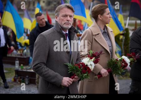 Leopoli, Ucraina. 23 febbraio 2024. Il primo ministro danese mette Frederiksen, a destra, e il marito Bo Tengberg, a sinistra, rendono omaggio ai soldati caduti sul campo di Marte all'interno del cimitero di Lychakiv, 23 febbraio 2024 a Leopoli, Ucraina. Credito: Pool Photo/Ufficio Stampa Presidenziale ucraino/Alamy Live News Foto Stock