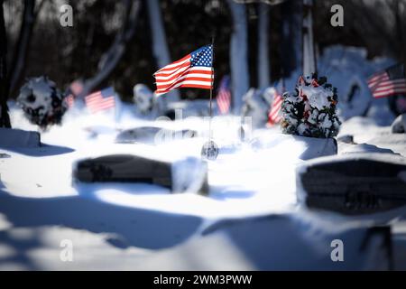 Bandiere americane in un cimitero con nevicate fresche in un cimitero del Wisconsin settentrionale. Foto Stock