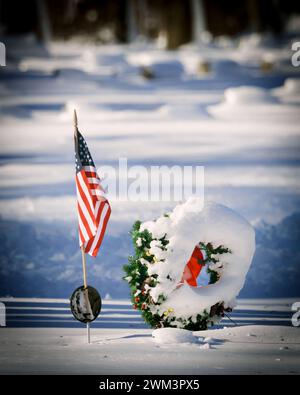 Una bandiera americana in un cimitero con nevicate fresche in un cimitero del Wisconsin settentrionale. Foto Stock