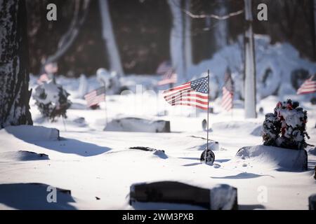 Bandiere americane in un cimitero con nevicate fresche in un cimitero del Wisconsin settentrionale. Foto Stock