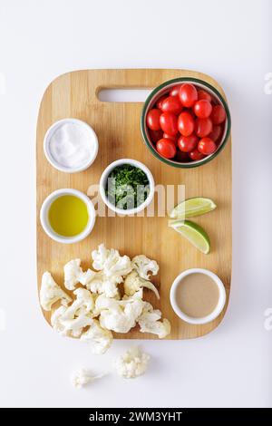 Pomodori di cavolfiore arrostiti e insalata di hummus su sfondo bianco tagliato a legna Foto Stock