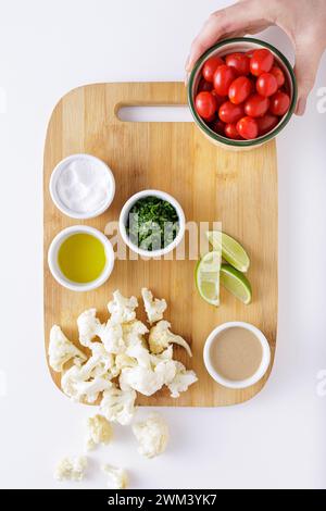 Pomodori di cavolfiore arrostiti e insalata di hummus su sfondo bianco tagliato a legna Foto Stock