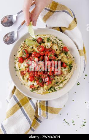 Arrostire pomodori cavolfiore e insalata di hummus su sfondo bianco Foto Stock