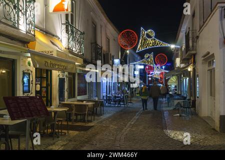 Strada di notte durante il periodo natalizio con ristoranti nel centro storico di Lagos, Algarve, Portogallo Foto Stock