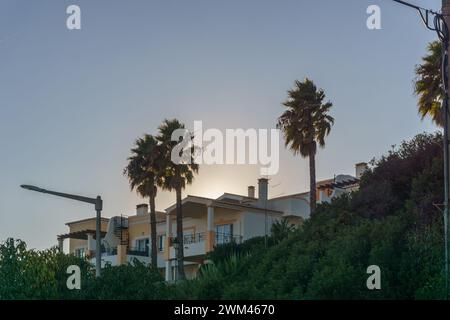 Ammira la villa con palme al tramonto nella piccola cittadina di pescatori di Salema, Algarve, Portogallo Foto Stock