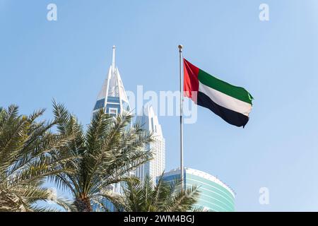 Bandiera che sventola in cima all'edificio moderno, simbolo nazionale degli Emirati Arabi Uniti. Giornata Nazionale e giornata della bandiera degli Emirati Arabi Uniti. La bandiera degli Emirati Arabi Uniti su Foto Stock