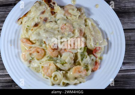 Cremoso mix di gamberi al forno, calamari di calamari, filetto di pesce, mozzarella, fette di peperone colorate e salsa bianca di farina, latte e gh Foto Stock