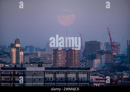 Londra, Regno Unito. 24 febbraio 2024. Meteo nel Regno Unito: La luna piena, nota anche come Luna di neve, secondo l'Almanacco dell'Old Farmer, imposta sulla città al 99,6% di illuminazione che si muove in direzione WNW. Crediti: Guy Corbishley/Alamy Live News Foto Stock