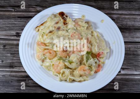 Cremoso mix di gamberi al forno, calamari di calamari, filetto di pesce, mozzarella, fette di peperone colorate e salsa bianca di farina, latte e gh Foto Stock