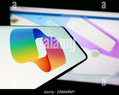 Telefono cellulare con logo del chatbot di intelligenza artificiale Microsoft Copilot davanti al sito Web aziendale. Messa a fuoco al centro del display del telefono. Foto Stock