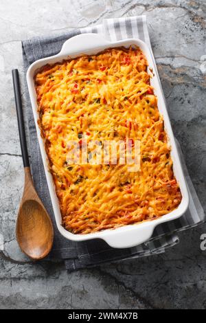 Casseruola di pollo King Ranch con pollo tirato, tortillas di mais, formaggio grattugiato, peperoni e peperoncini verdi piccanti da vicino in un piatto da forno su una marna Foto Stock