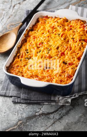 Casseruola di pollo King Ranch con pollo tirato, tortillas di mais, formaggio grattugiato, peperoni e peperoncini verdi piccanti da vicino in un piatto da forno su una marna Foto Stock