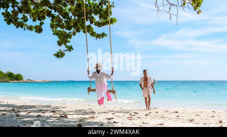 Un paio di uomini e donne in un'altalena sulla spiaggia di Koh Samet Island Rayong Thailandia, una coppia in luna di miele in Thailandia che si diverte sulla spiaggia con un'altalena in una giornata di sole Foto Stock