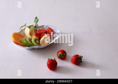 Macedonia di frutta con fragole, kiwi e banane in una ciotola su sfondo bianco Foto Stock