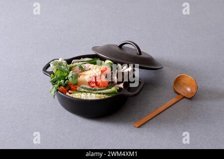 Cibo coreano in pentola nera su sfondo grigio Foto Stock