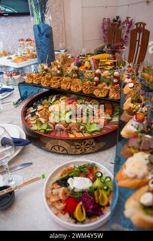 Un sontuoso buffet che offre un ricco assortimento di pesce fresco, sushi, insalate, frutta e pasticcini, splendidamente disposto su un tavolo bianco immacolato Foto Stock