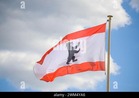 La bandiera di Berlino sventolava nel vento. Bandiera dello stato tedesco di Berlino che vola su un'asta. Orso nero su sfondo bianco. Foto Stock