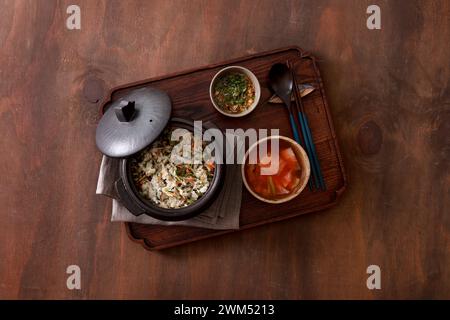 Cucina coreana. Riso con verdure in una pentola su fondo di legno Foto Stock